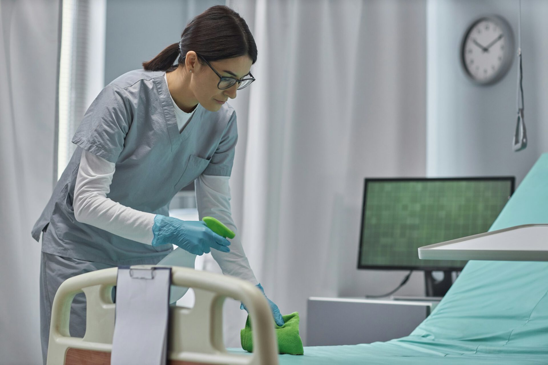 Nurse cleaning the bed in hospital ward